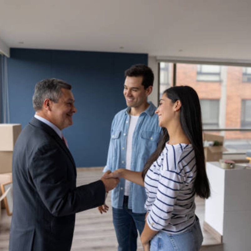 Real Estate Agent selling an apartment to a couple and closing the deal with a handshake - real estate concepts